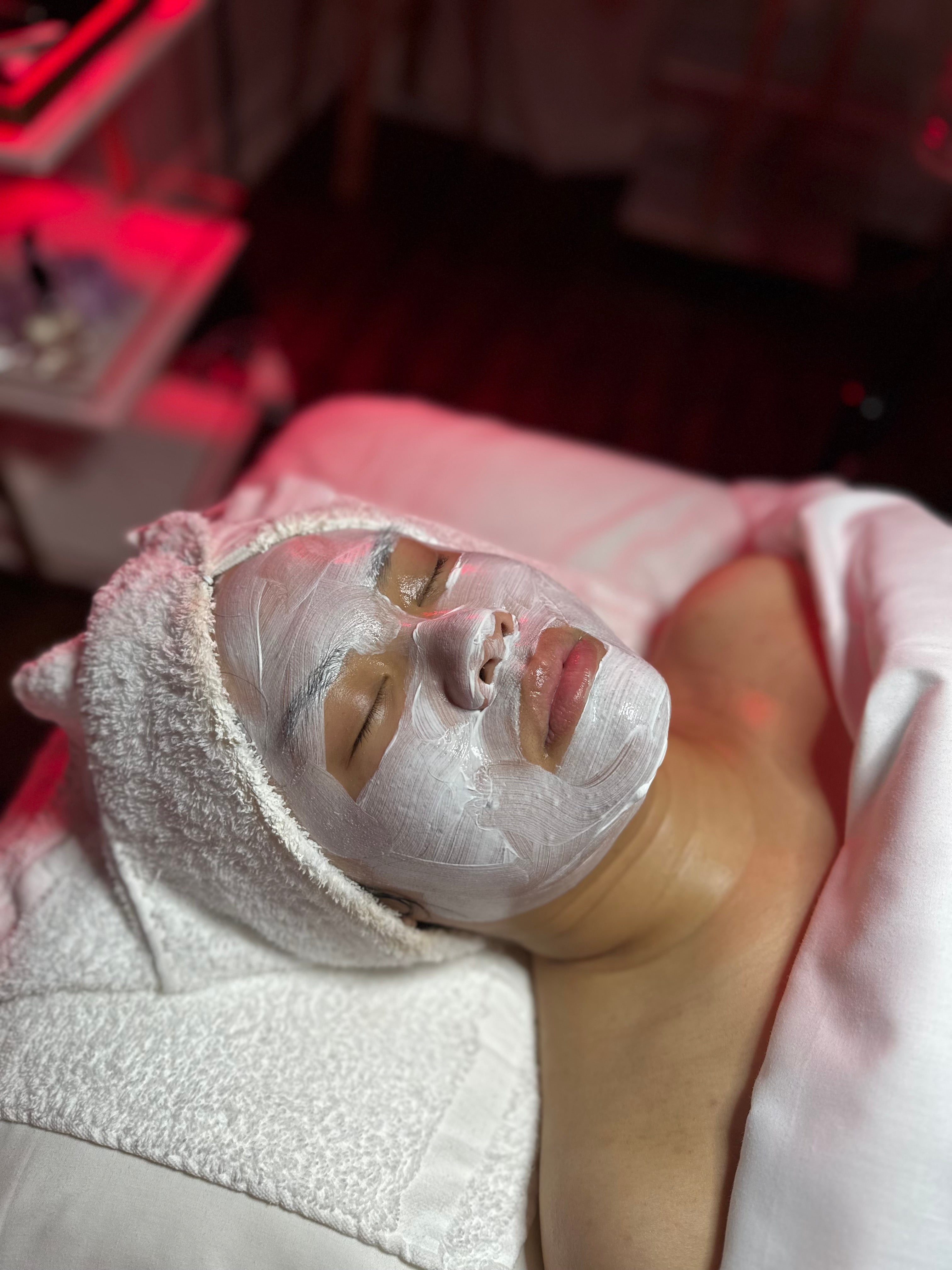 Person receiving a facial treatment with a towel on their head in a spa setting.