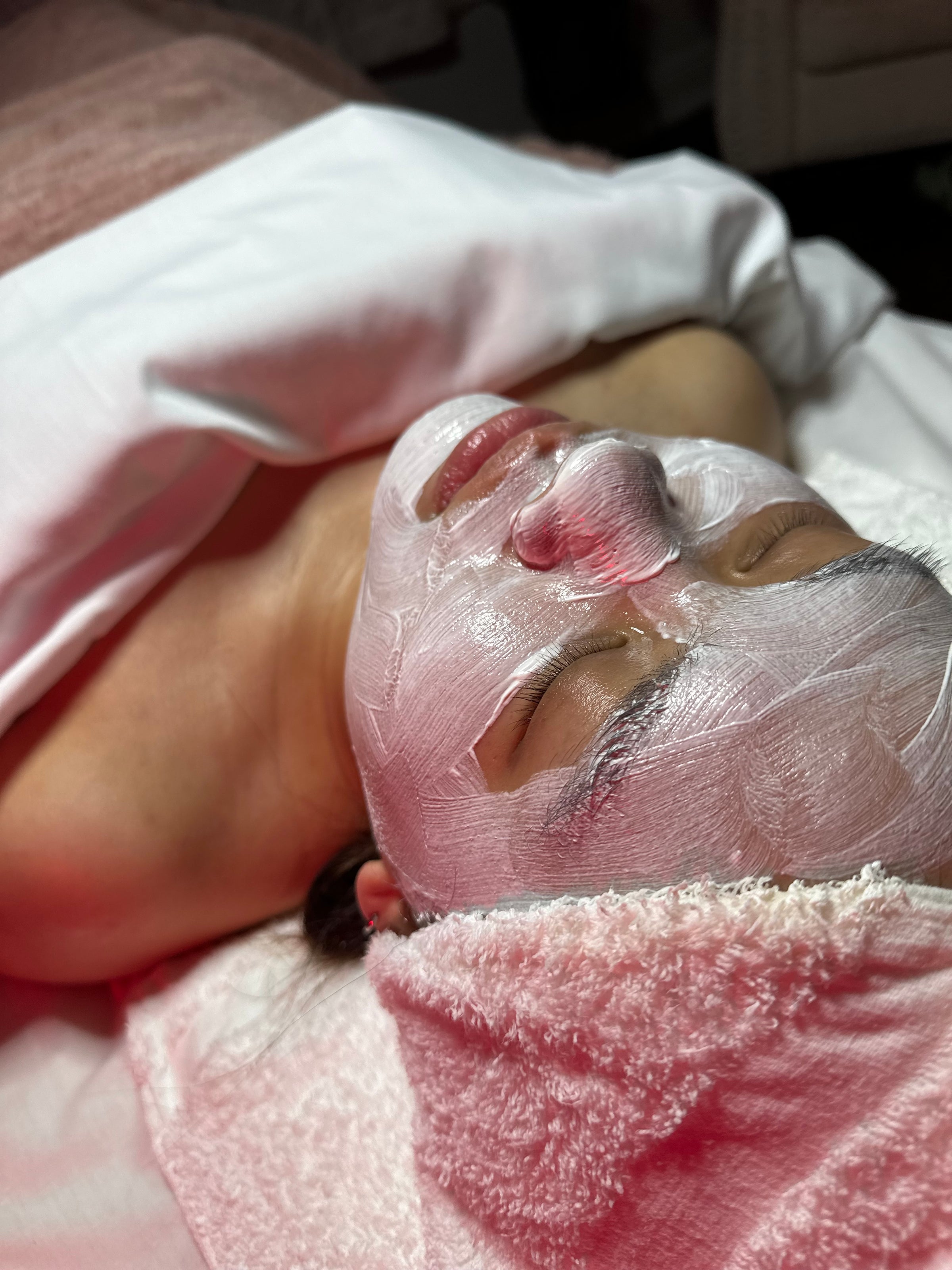 Person receiving a facial treatment with a face mask on.